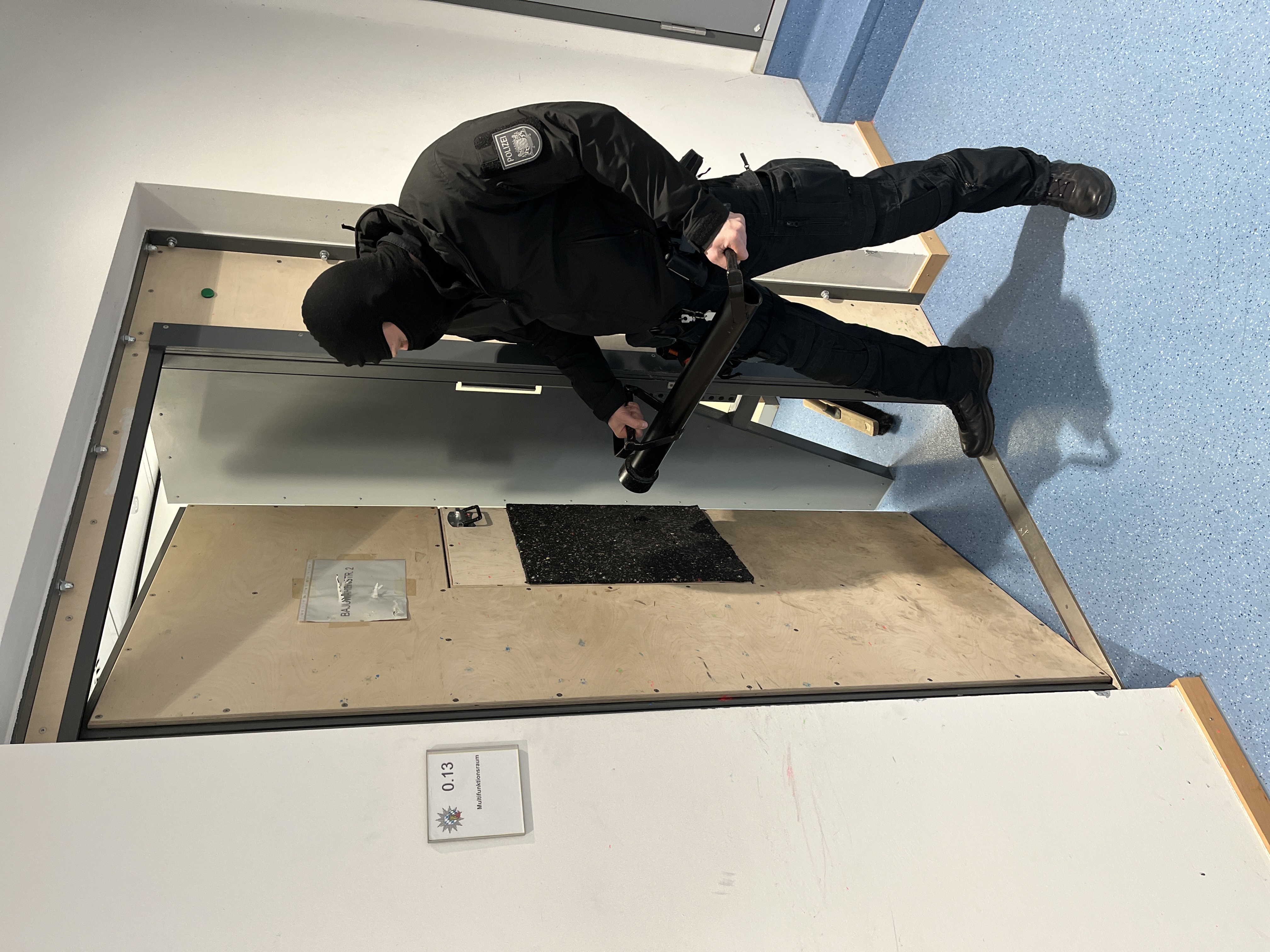 Polizeibeamter mit Ramme an der geöffneten RAMMTÜR